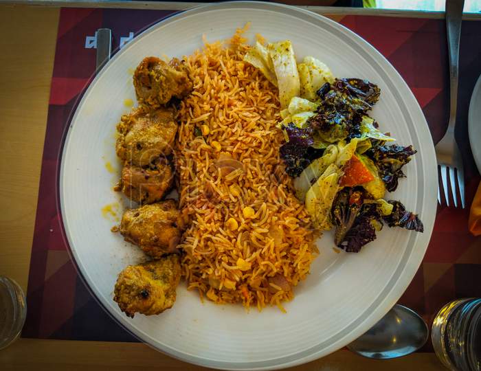 Tandoori kebab chicken with schezwan corn rice, A continental dish served on white plate with well garnish