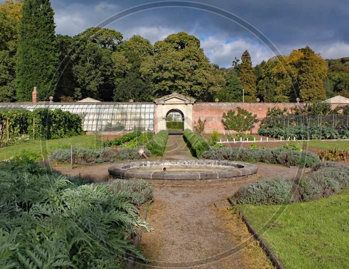 Walled Kitchen Garden With A Pathway And A Circular Fountain.