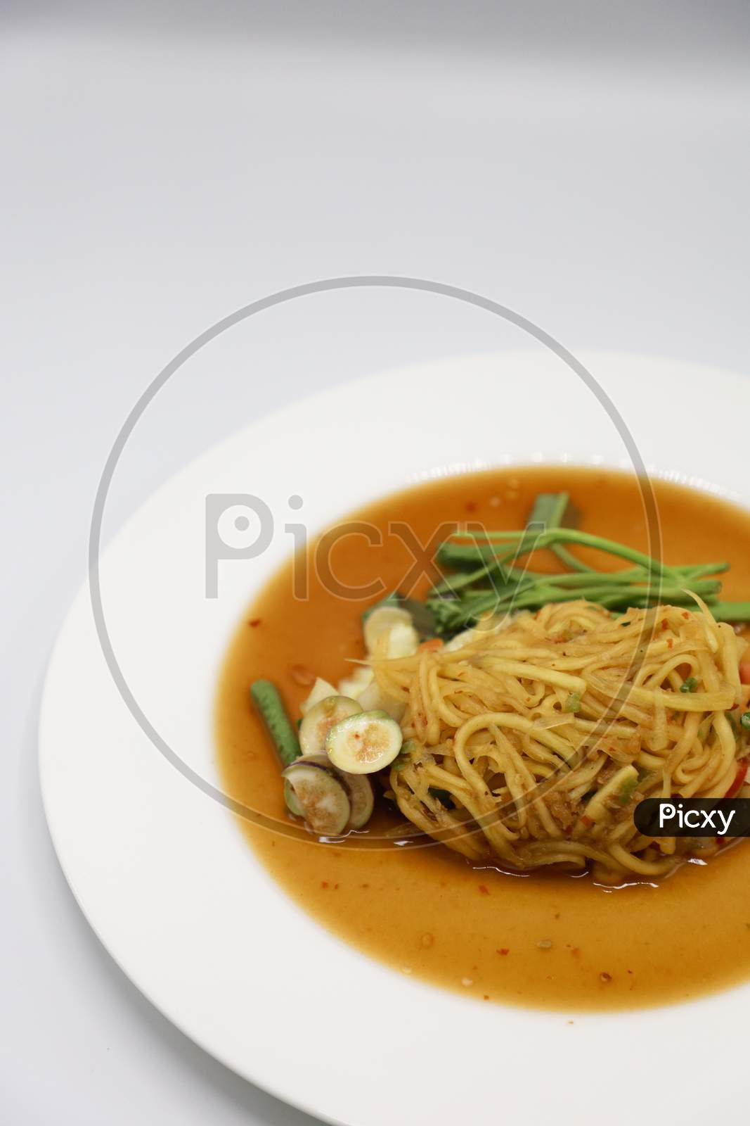 Asian vegetarian food udon noodles with Beijing cabbage, carrots, green beans, bell pepper, onions  served in a Plate isolated with White Background