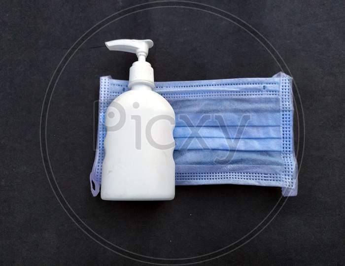face mask and hand sanitizer isolated on black background
