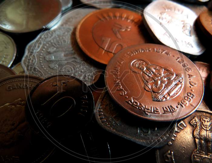 Closeup shot of coins displaying Indian currency of various values on a dark background
