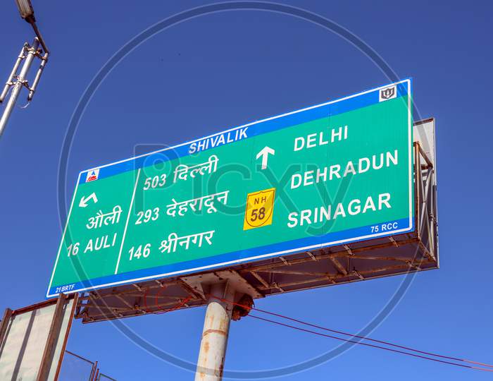Auli ,Uttarakhand /India-March 16,2020: Road Direction Sign Board At Delhi -Uttarakhand Highways Roads Written In English  And Hindi Language  Near  Lamp Post