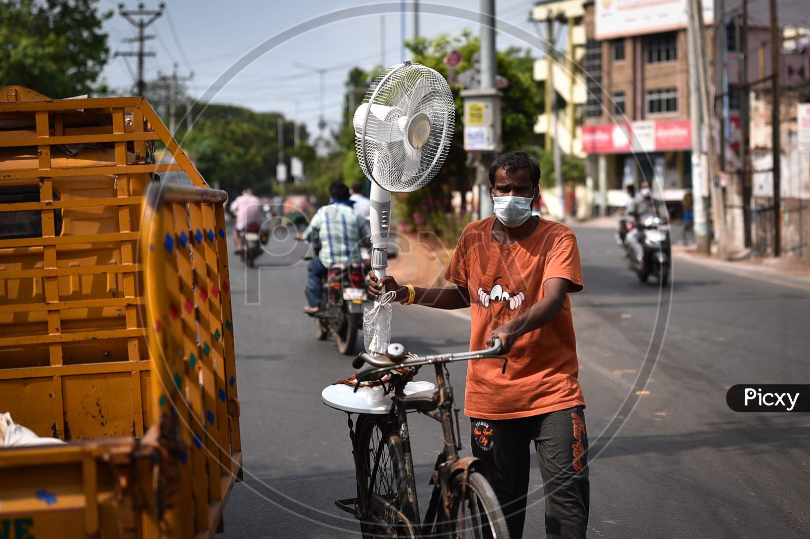 A Man Wearing A Face Mask Carries A Table Fan For The Summer Season, During The Nationwide Lockdown Imposed In The Wake Of Coronavirus Pandemic, In Vijayawada