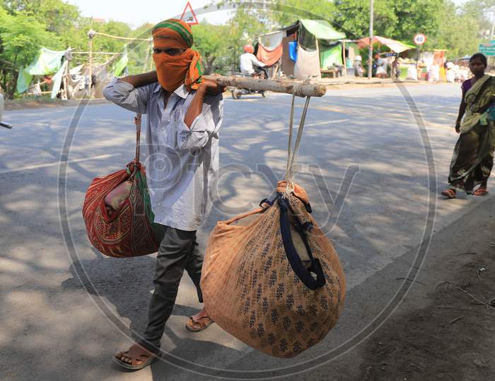 A migrant laborer carrying goods walks on the road during an extended nationwide lockdown to slow the spread of the Coronavirus disease, in Prayagraj, May 4, 2020.