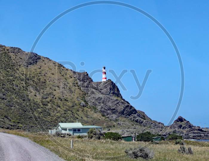 The Red And White Striped Lighthouse At Cape Palliser On North Island, New Zealand Stands High On The Cliffs. The Lighthouse Was Built In 1897 And Was Originally Fueled By Oil.