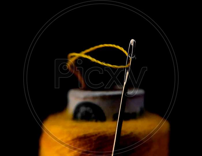 Needle and yellow thread focused on needle