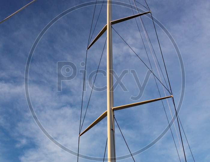 The Mast And Rigging Of A Racing Yacht Stands Out Against The Clear Blue Sky.