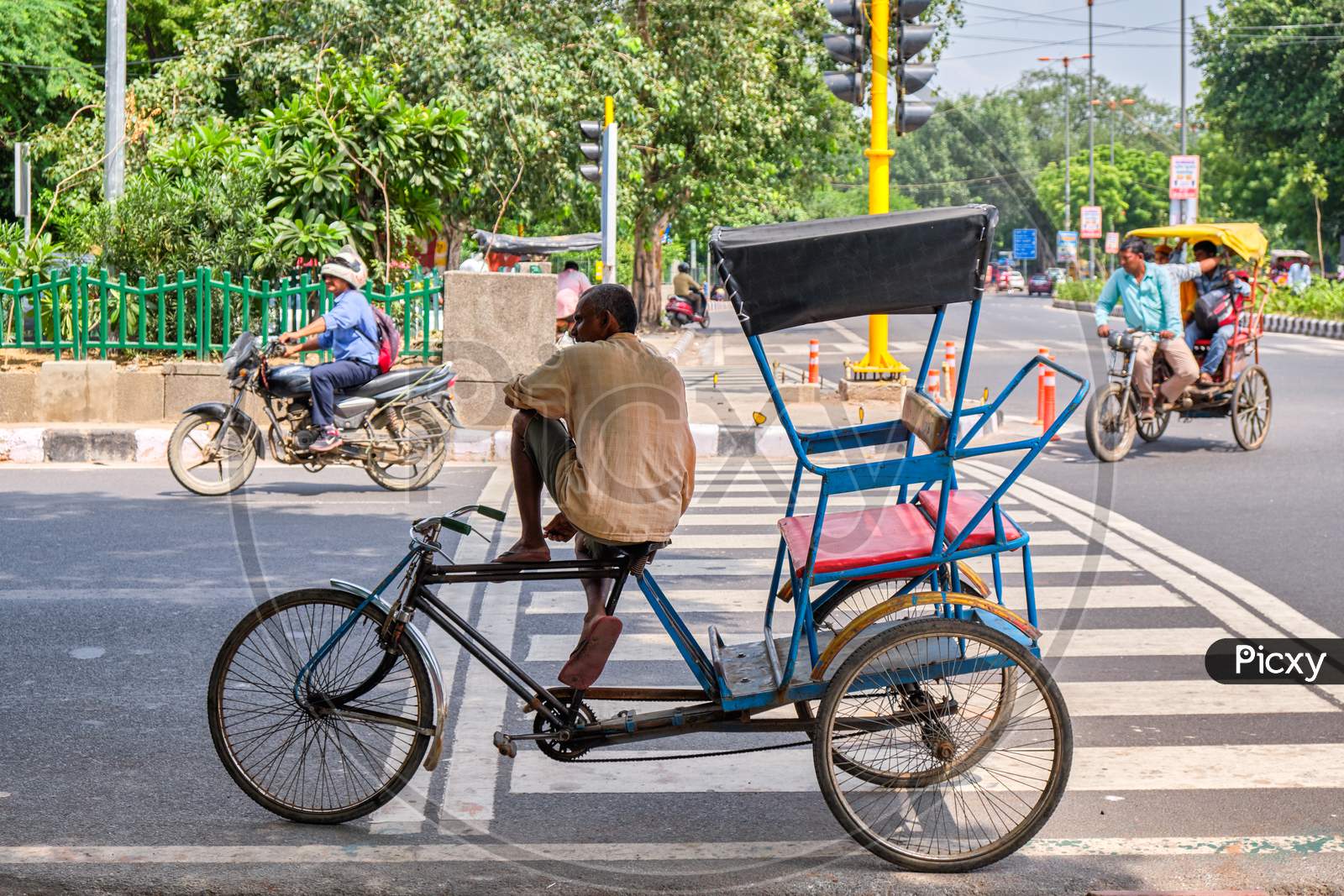 Driver Sitting On His Bicycle Rickshaw In The Streets Of New Delhi, India
