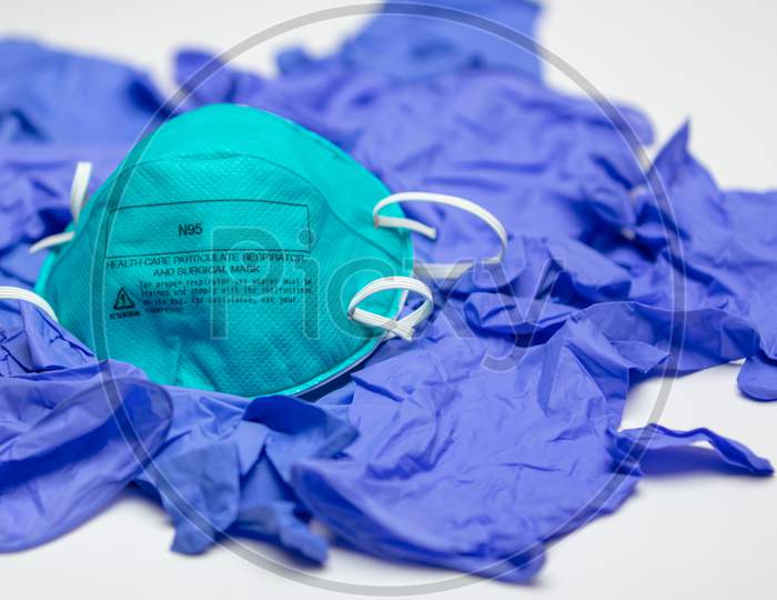 A Turquoise N95 Particulate Respirator And Surgical Mask On Top Of Many Medical Gloves.