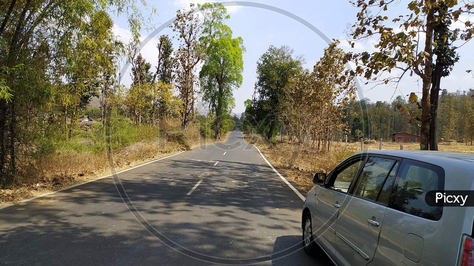 Empty Road in forest and car parked in corner