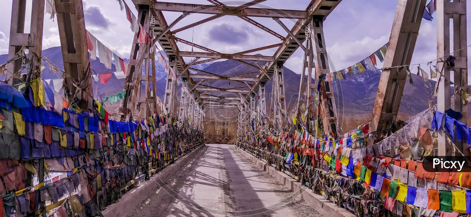 Colourful Buddhist prayer flags on a bridge above Indus river in the Himalayan mountain, Leh, Ladakh, India