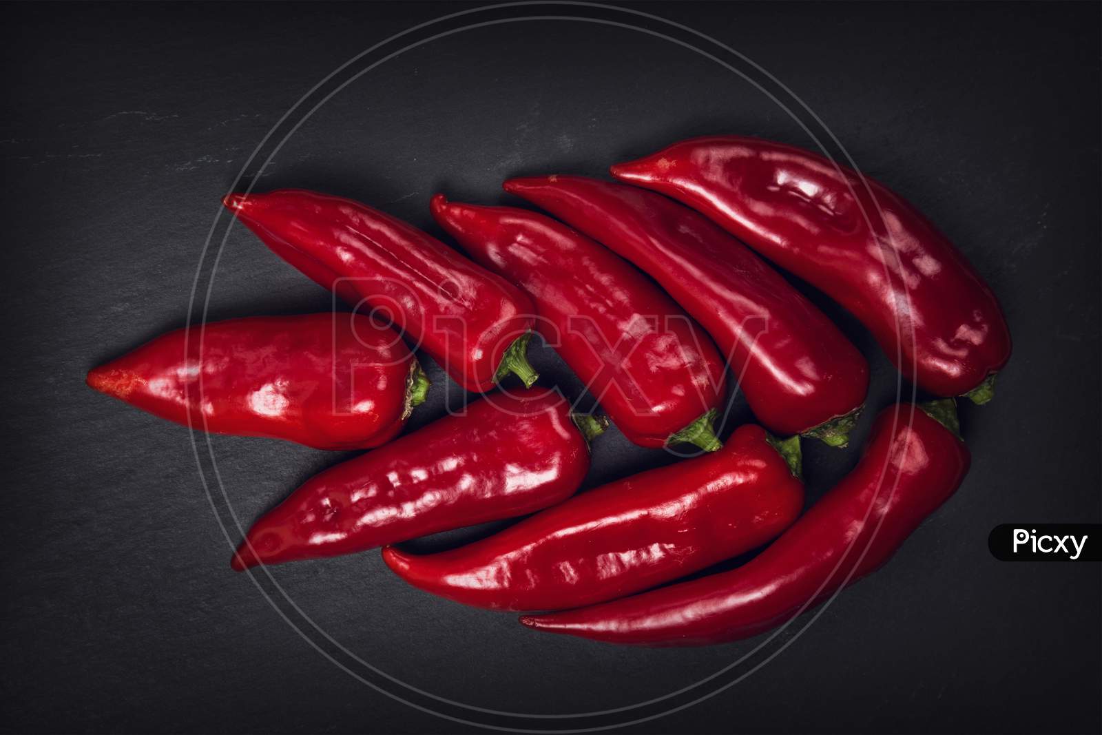Close-Up Of Red Chili Peppers Against Black Background Long Red March Inspirational Scene
