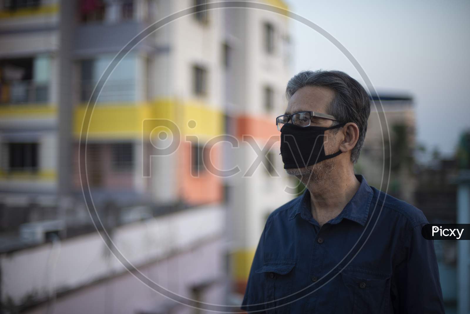 Portrait of an Indian old man wearing corona preventive mask on a rooftop  in home isolation.Indian lifestyle, disease and home quarantine.