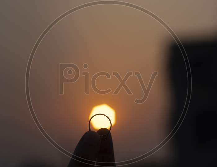 Silhouette of fingers holding a ring during sunset. Back light photography.