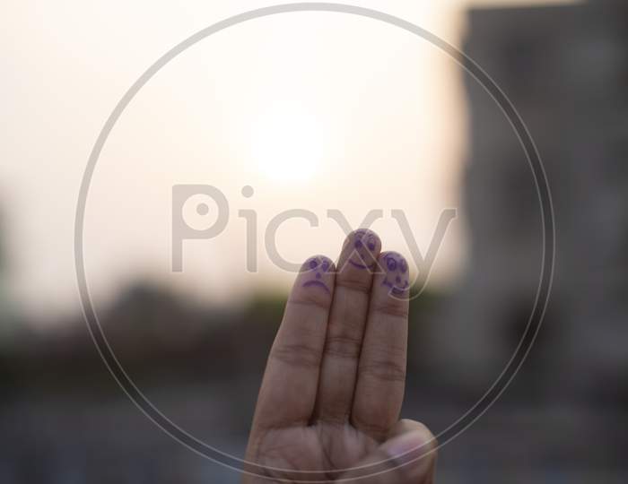 Artistic human face drawn on the fingertips on a natural background in a summer afternoon.