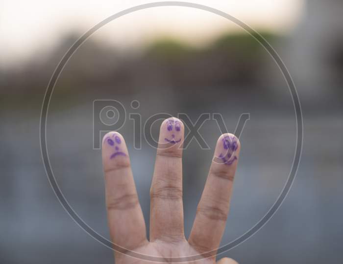 Artistic human face drawn on the fingertips on a natural background in a summer afternoon.