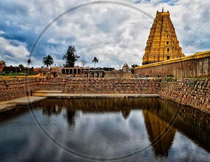 Virupaksha temple of Hampi with reflection under open blue sky.