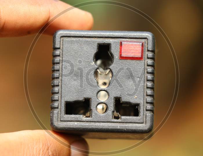Universal Plug Adapter Held In Hand Which Is Used To Connect Odd Type Pin Plugs