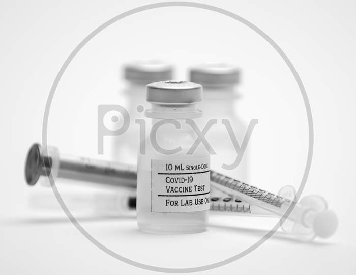 Three Covid-19 Test Vaccine Vials And Three Syringes Isolated On A White Background.