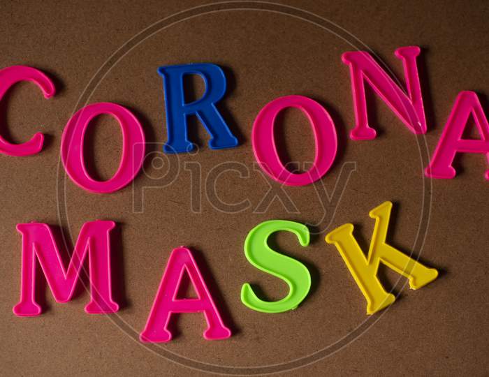 'CORONA MASK' written on a brown wooden background with lines of shadow.