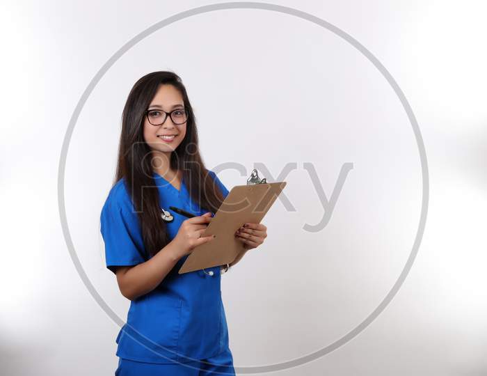 A Young Nurse Wearing Glasses Takes Notes On Her Clip Board.