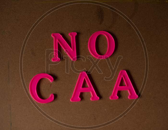 'NO CAA' written on a brown wooden background with lines of shadow.