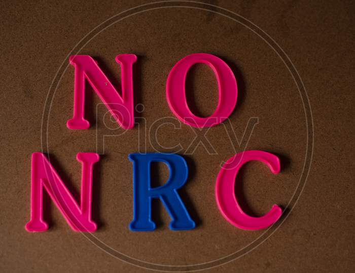 'NO NRC' written on a brown wooden background with lines of shadow.