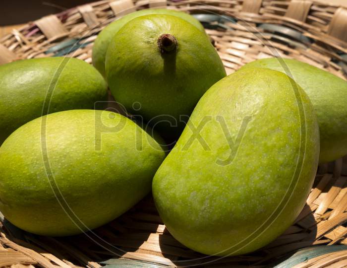 side view of raw mangoes in bamboo basket