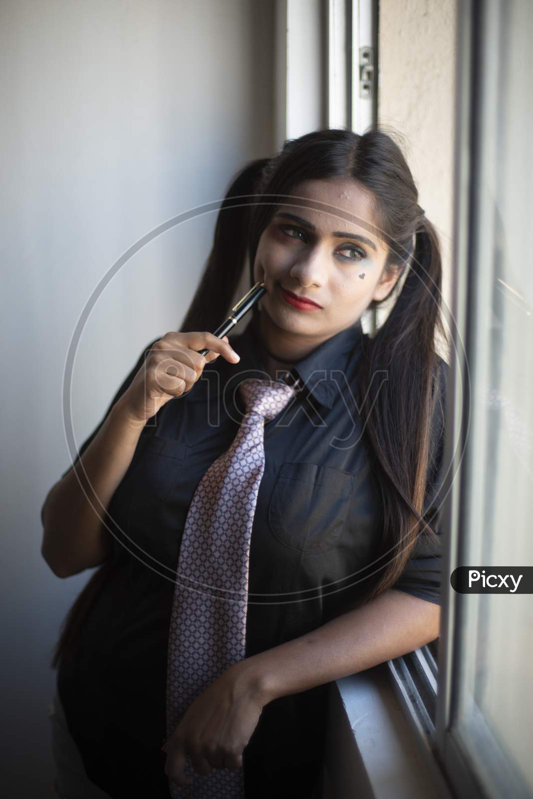 Portrait of an young Indian brunette girl in black corporate suit with spectacles and pen in front of a glass window in white background. Indian lifestyle and corporate