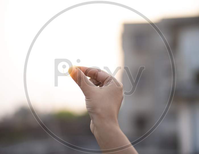 Image of fingers holding a ring during sunset. Back light photography.