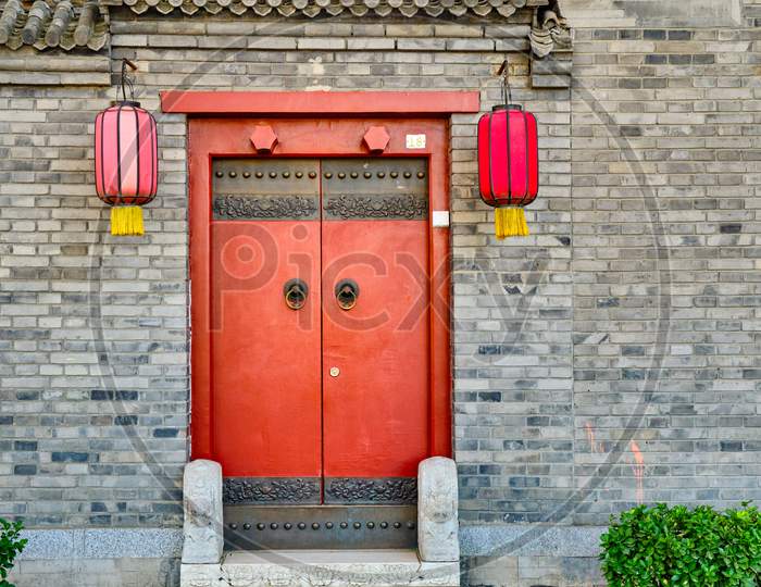 Traditional Hutong Alley In Beijing, China, Vintage Door With Red Lanterns On An Old Brick Building