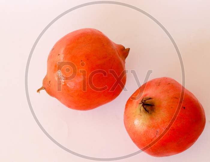 Ripe pomegranates and leaves on wooden background
