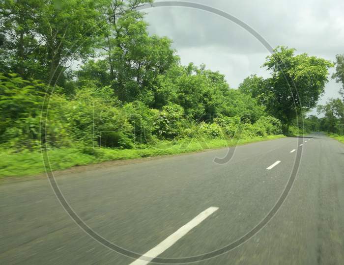 Empty Road With Cloudy Atmosphere And Greenery Both Side In India.