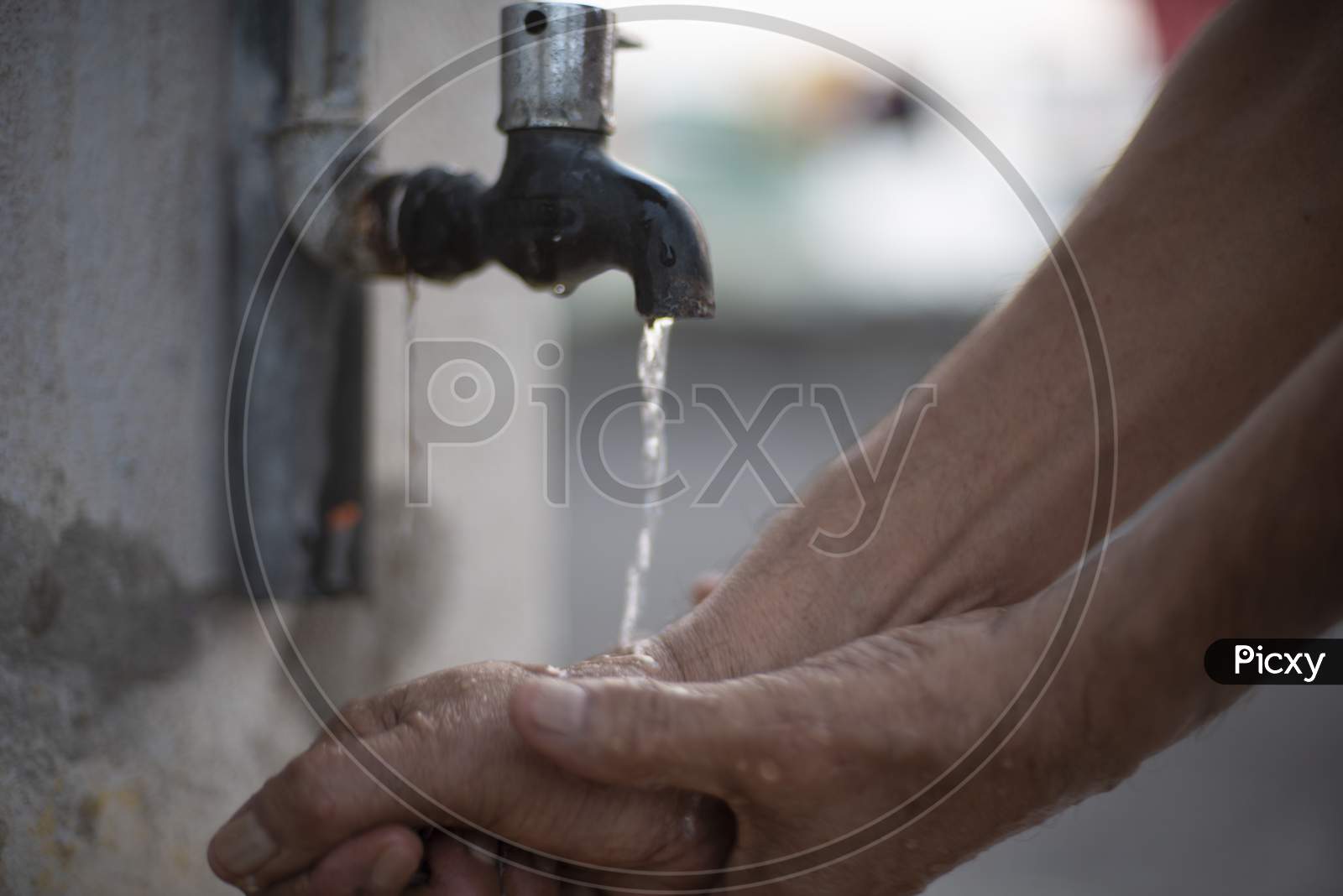 A person washing hands in tap water using sanitizer to prevent corona virus. Indian lifestyle, covid 19, pandemic