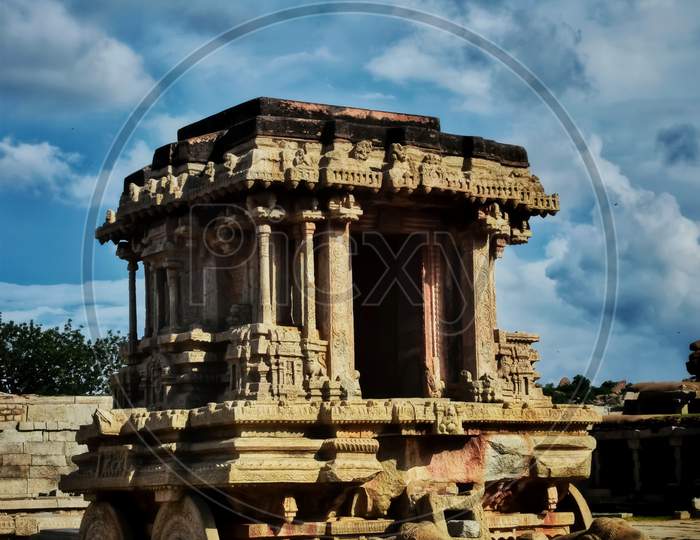Stone chariot of Hampi under open blue sky.