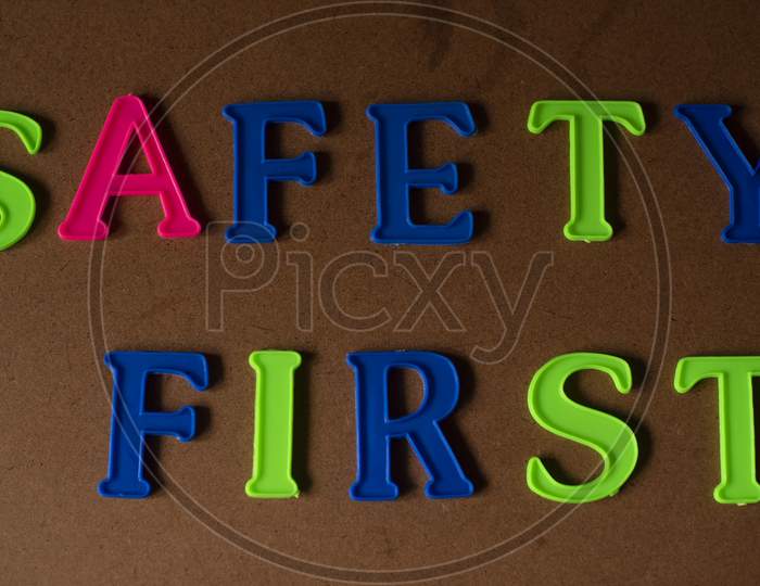 'SAFETY FIRST' written on a brown wooden background with lines of shadow.