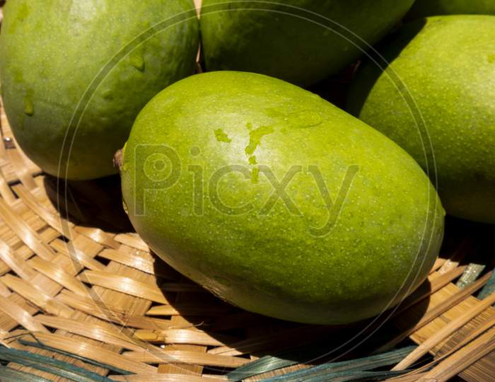 raw green mangoes in bamboo basket
