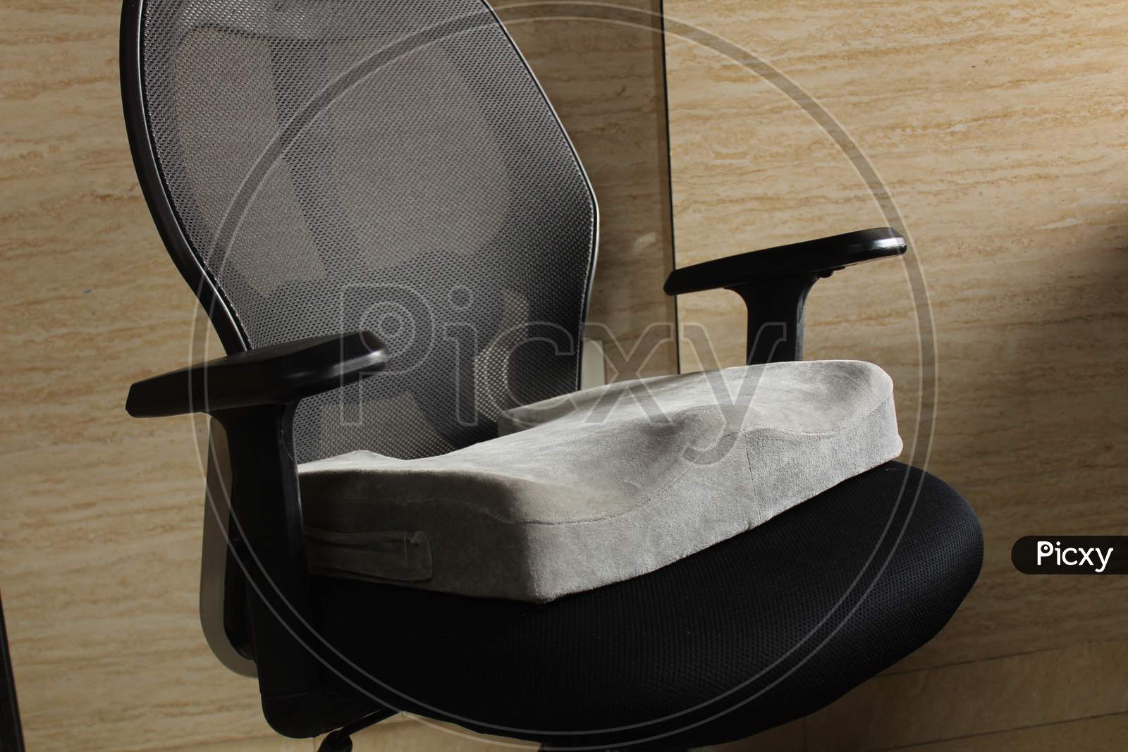 Grey Memory foam sciatica/coccyx cushion in black office chair in home