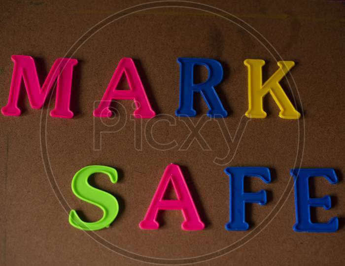'MARK SAFE' written on a brown wooden background with lines of shadow.
