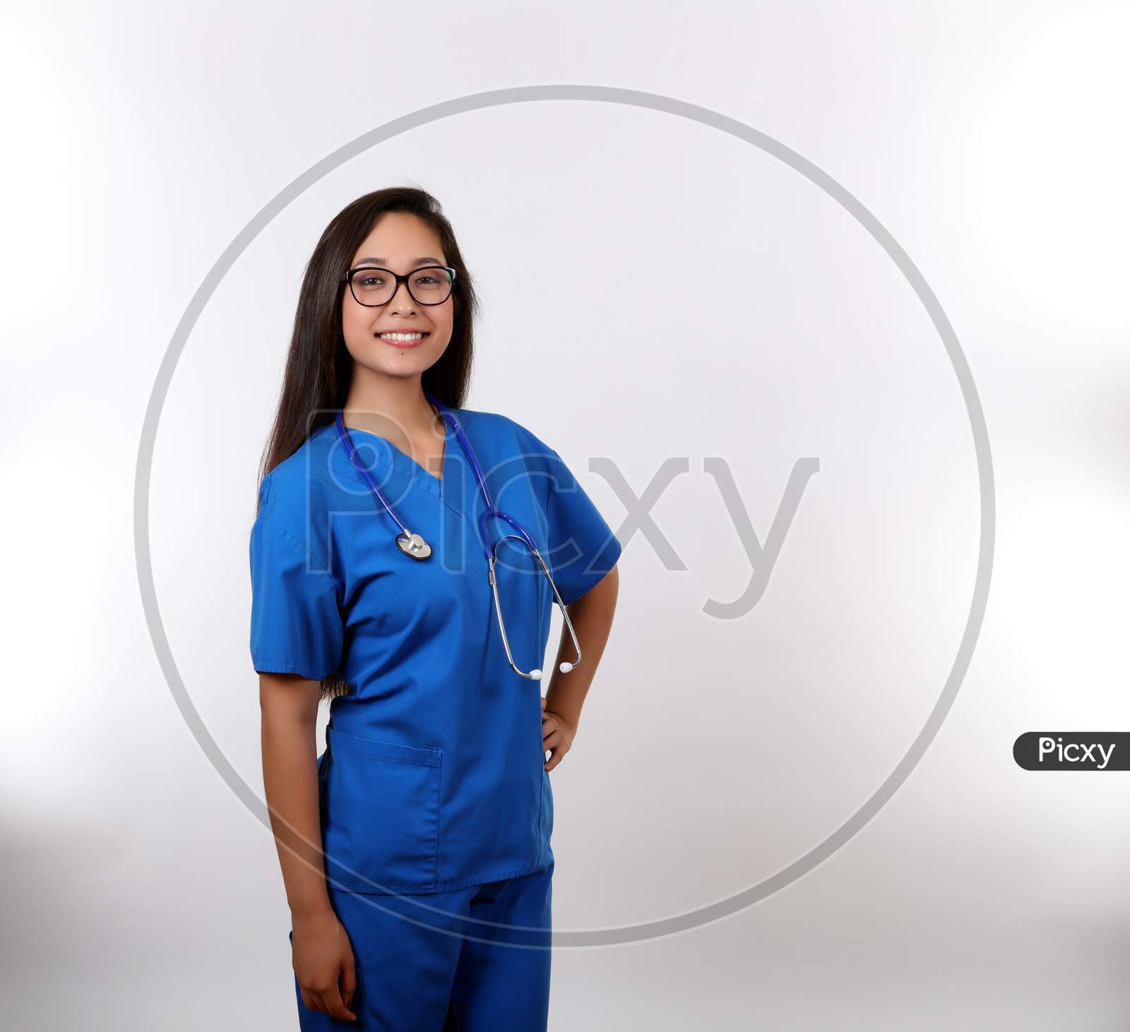 A Cheerful Nurse In Blue Scrubs Ready To Help.