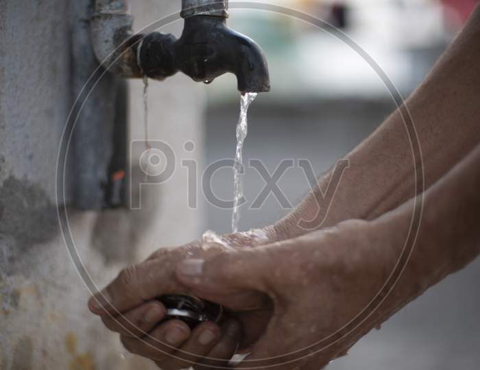 A person washing hands in tap water using sanitizer to prevent corona virus. Indian lifestyle, covid 19, pandemic