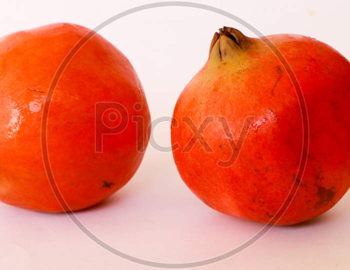 Ripe pomegranates and leaves on wooden background
