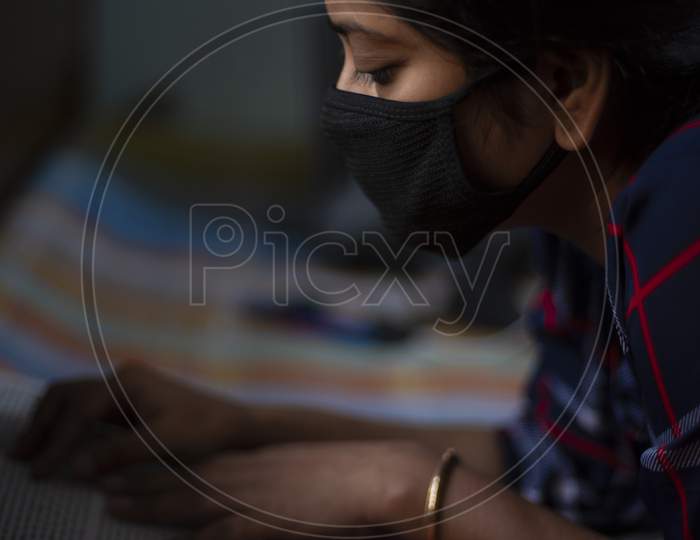 Portrait of an Indian young woman wearing corona preventive mask in home isolation in front of a window. Indian lifestyle and disease.