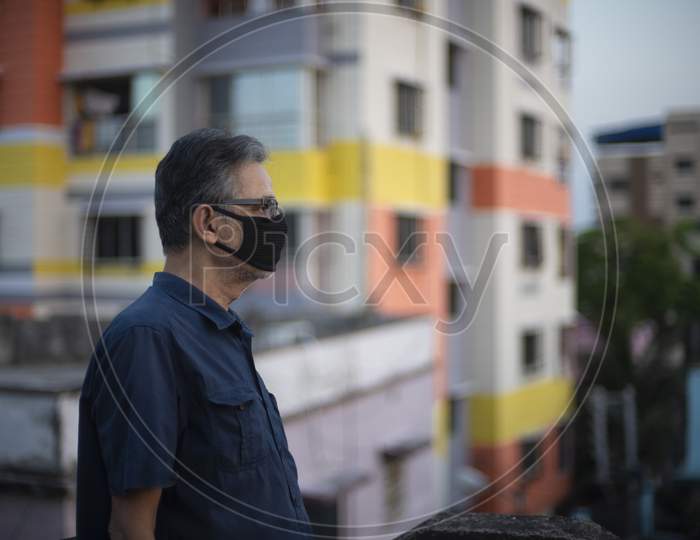 Portrait of an Indian old man wearing corona preventive mask on a rooftop  in home isolation.Indian lifestyle, disease and home quarantine.