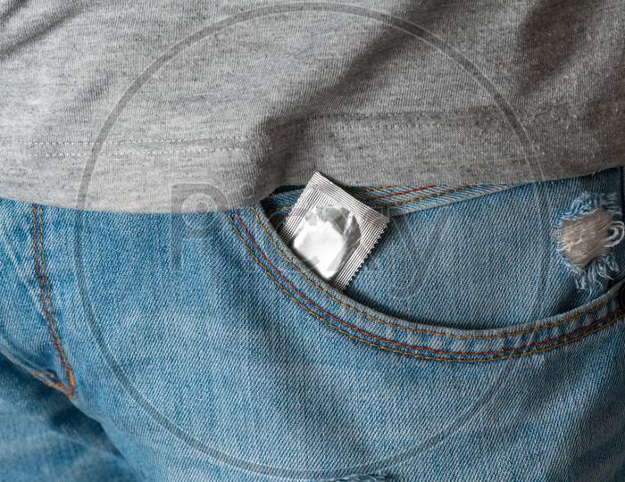 Condom In The Pocket Of Blue Men Jeans With A Zipper. Concept Of Sex, Seduction, Erotica, Protection, Safe Sex