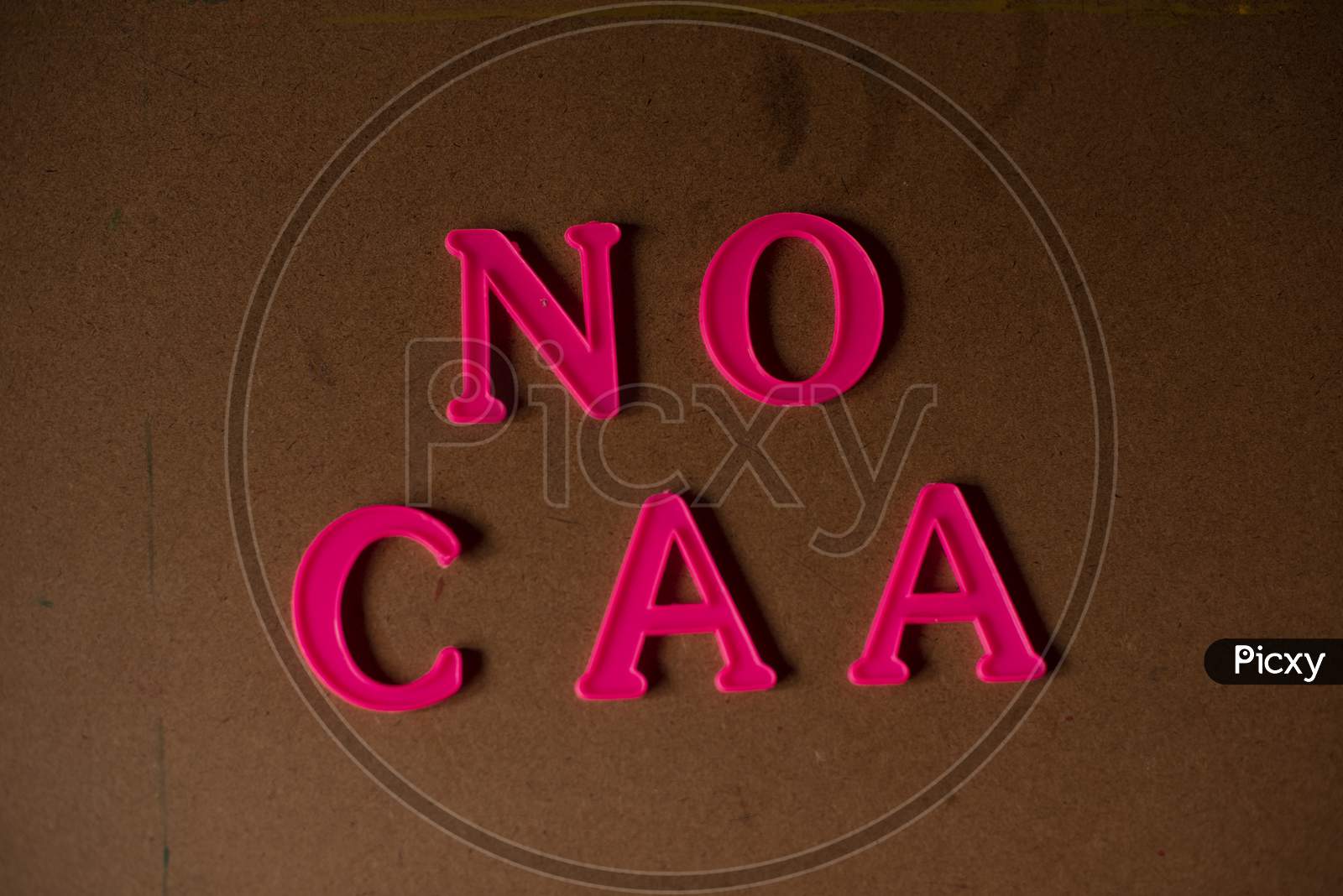 'NO CAA' written on a brown wooden background with lines of shadow.