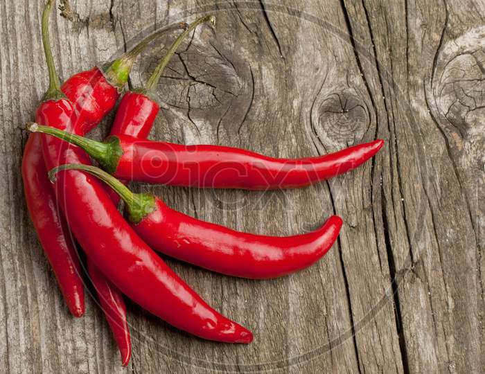 Close-Up Of Red Chili Peppers Against Wood Background Long Red March Inspirational Scene