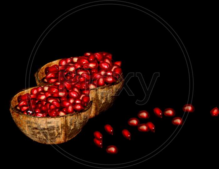 pomegranate in recycled coconut bowl in black background