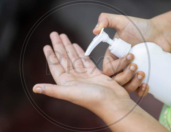 Child'S Hand Holding Sanitizer Bottle