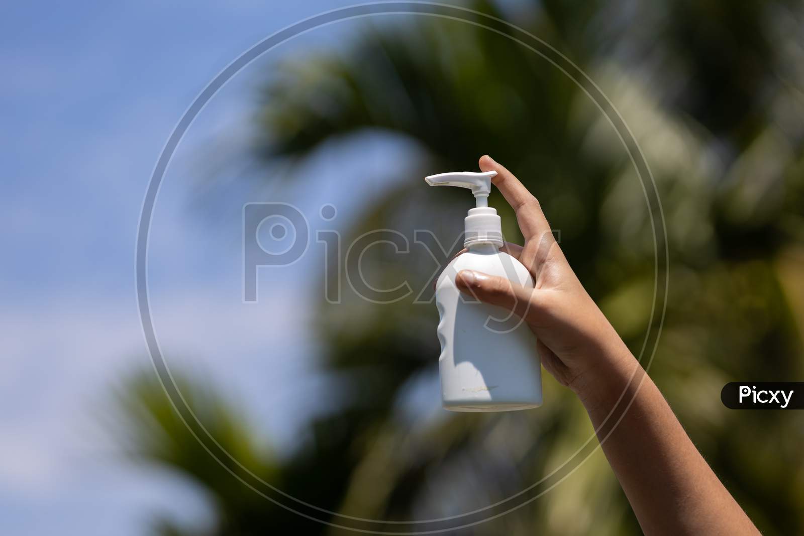 Child'S Hand Holding Sanitizer Bottle Outdoors